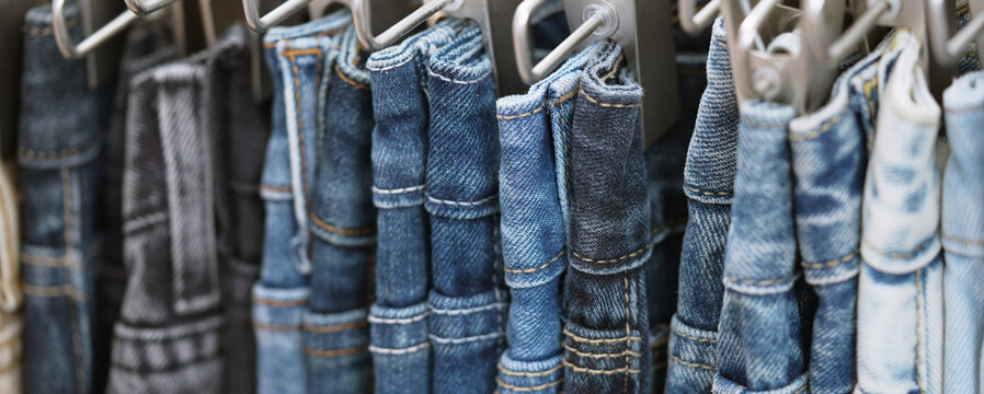 A close up of a blue denim row of jeans hanging on a rack. of different colors and styles. Concept of variety and choice.	
