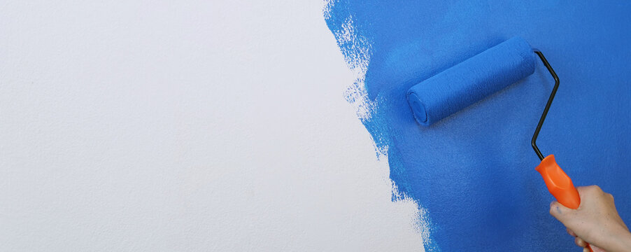 Roller Brush Painting, Worker painting on surface wall Painting apartment, renovating with blue color paint. Leave empty copy space white to write descriptive text beside.