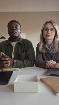 POV of young adult Caucasian woman and African American man setting webcam, talking during business video call. Ideal for remote work advertising, vertical