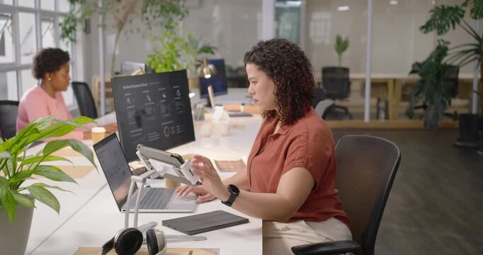 Diverse office team, woman in rust top after dashboard ping, adjusting tablet and typing on laptop