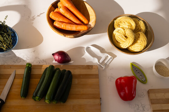 Cluster of dark green zucchinis are resting on wooden cutting board; chef's knife nearby