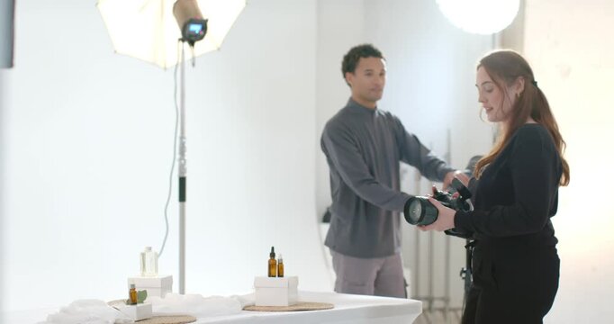 Studio crew photog entering checking DSLR asst moving props stylist adding green for ad, copy space