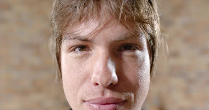 Man on set taking cue, shifting expression and smiling for headshot with brick wall soft lighting