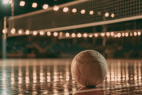 Worn basketball resting on a polished indoor court under warm arena lights, sports photography, gym floor, ball texture, training and game day atmosphere.