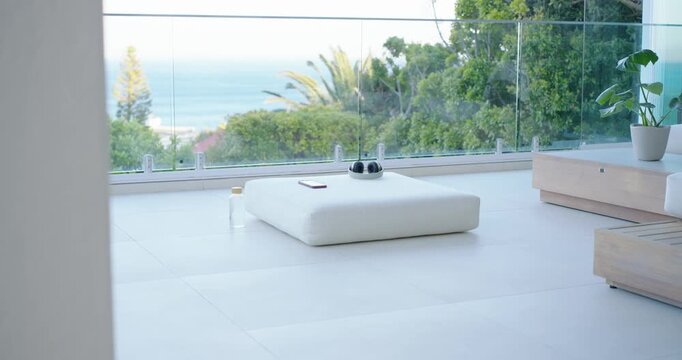 Camera starting slide is showing white ottoman with headphones, phone by glass exposing ocean view