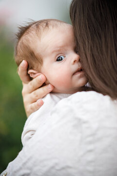 Mother kissing and hugging cute newborn baby in the garden, close up. Love, care and family in countryside concept. Happy Mothers day! Adoption and maternity