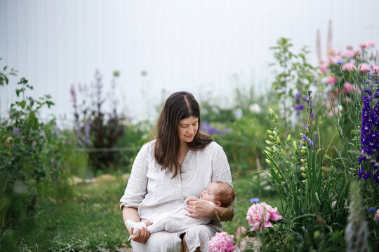 Happy Mothers day! Mother hugging cute newborn baby among flowers in the garden. Love, care and family in countryside concept. Adoption and maternity