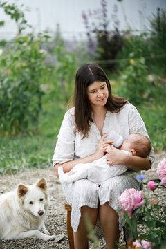 Happy Mothers day! Mother hugging and feeding cute newborn baby  with bottle in the garden. Love, care and family in countryside concept. Adoption and maternity