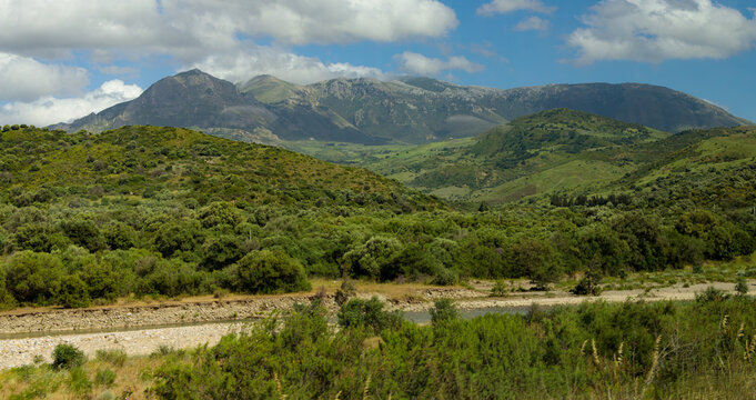 green hills and mountain range above dried river stream place country side summer scenery view