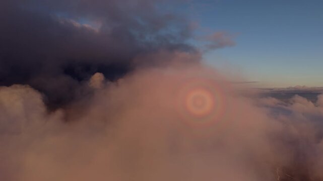 Aerial rotating flight through dramatic golden hour clouds at twilight 