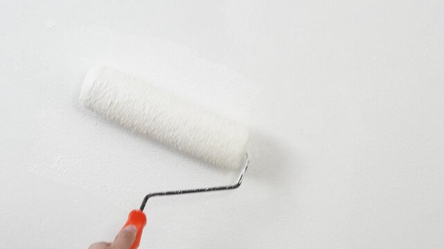 Roller Brush Painting, Worker painting on surface wall Painting apartment, renovating with white color paint. Leave empty copy space  to write descriptive text beside.