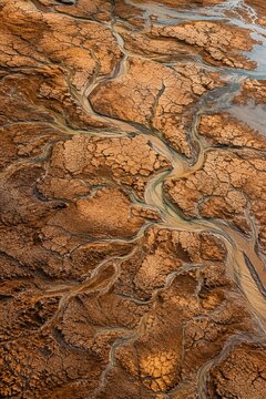 Aerial view of branching river channels and dry cracked earth terrain in a remote wilderness landscape.