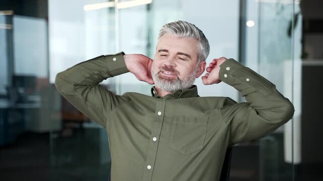 Close-up of businessman relaxing with closed eyes after finishing work. Happy mature man smiling with hands behind head, feeling peaceful, satisfied and refreshed during break at office workplace.