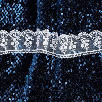 White lace trim on navy sequin fabric texture pattern