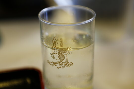 A glass cup with Awamori branding holds a cool beverage.