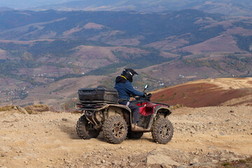 A man riding a red ATV quad bike on a rocky mountain trail on the Borzhava Ridge. © Аліна Костюк