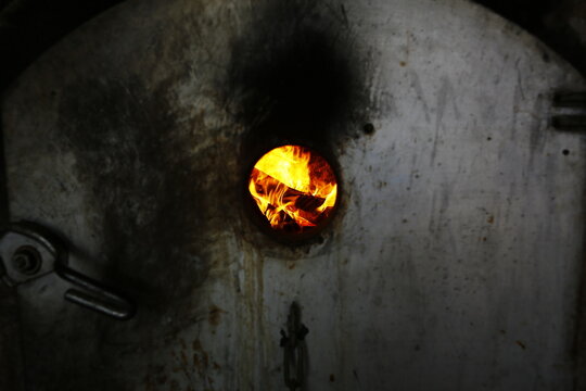 Flames blaze through the observation hole of a traditional brick furnace.