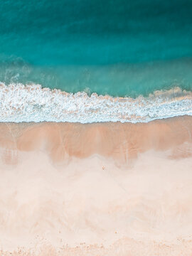 Aerial view of Aomak Camping Site with turquoise waves crashing on the white sand shore in Hadibu, Socotra, Yemen.