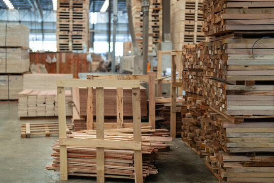 Lumber stacks inside the timber warehouse stand beside a wooden crate, with long wood planks visible in layered piles.