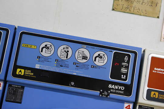 Operation panel of a commercial SANYO gas dryer in a coin laundromat with step-by-step instructions.