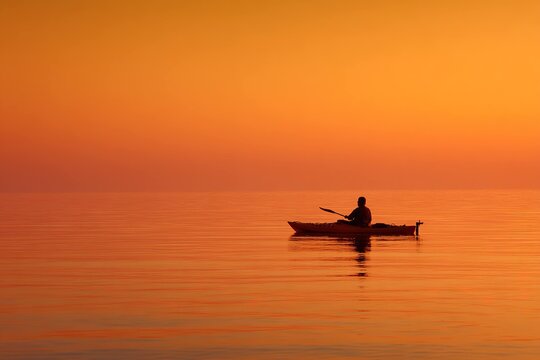 minimalistic kayaking silhouette against orange sky