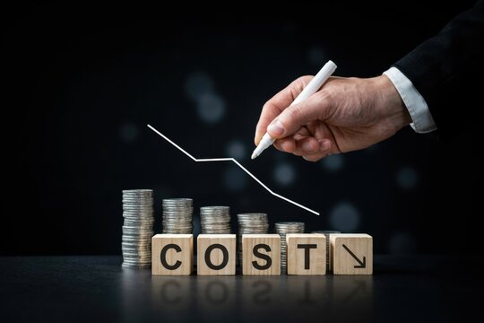 Hand drawing a declining trend line over wooden blocks spelling cost with downward arrow