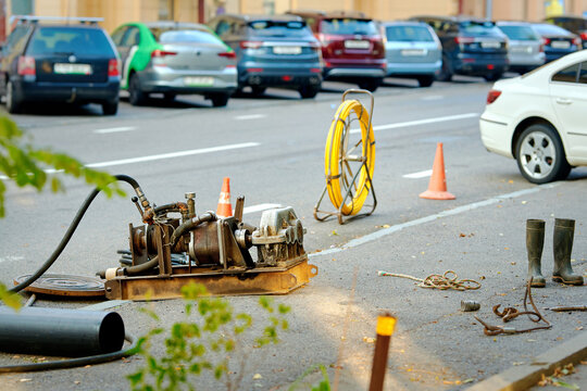 Cable pulling operation with specialized tools to install fiber optics into city ductwork. Fiber cable rod for laying lines through manhole during sewer maintenance and communication line upgrade