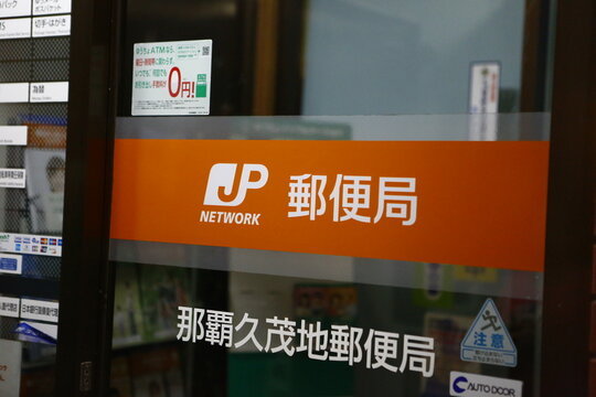 The glass entrance of Naha Kumoji Post Office displays the official JP Network logo and operational signs.