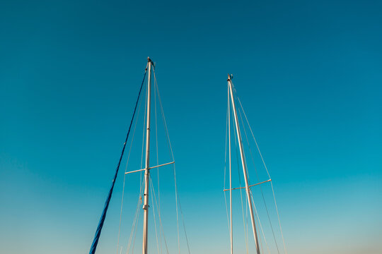 Tall sailboat masts pointing toward morning sky in a quiet marina. Concept of sailing, summer luxury travel, yachting lifestyle, maritime adventure, and peaceful coastal evening.