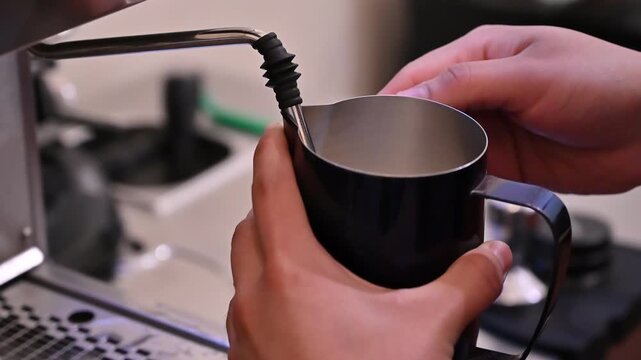 Barista steaming milk in a metal pitcher