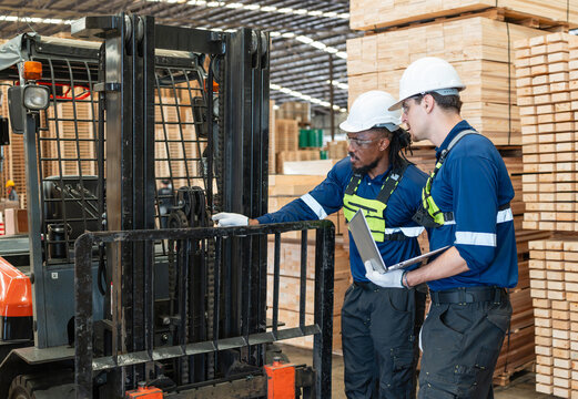 During lumber inventory checks, warehouse staff include two men inspecting a forklift with a laptop and two other workers.