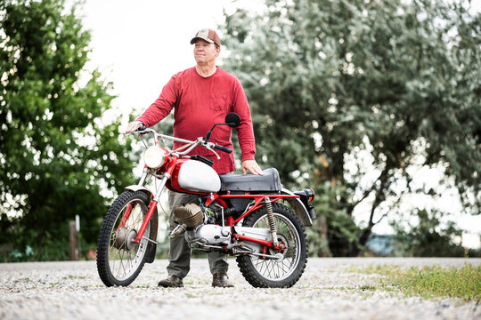 Portrait of a Senior Man Sitting on a Vintage 1970s European Motorcycle Looking at the Camera