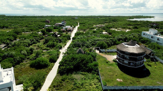 Aerial view of round thatched building beside a sandy track in Mexico