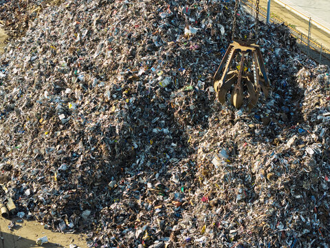 Aerial view of a large scrap metal pile being processed by a mechanical claw in the United Kingdom.