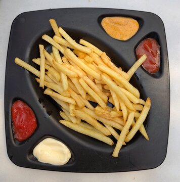 Vista superior de una bandeja con una raci&oacute;n de patatas fritas con huecos para diversas salsas 