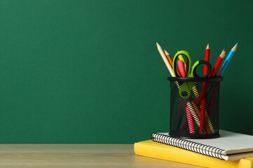 Metal pencil holder filled with colored pencils, with colorful school supplies on wooden table © Sunlight