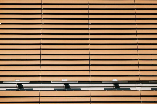 Architectural exterior of a contemporary building with light brown horizontal wooden slats creating a repeating textured surface