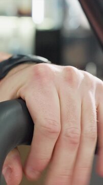 Close up shows hands repeatedly grasping exercise machine handlebar. focus is steady grip with visible skin texture details and slight movement of hand over time emphasizing calluses