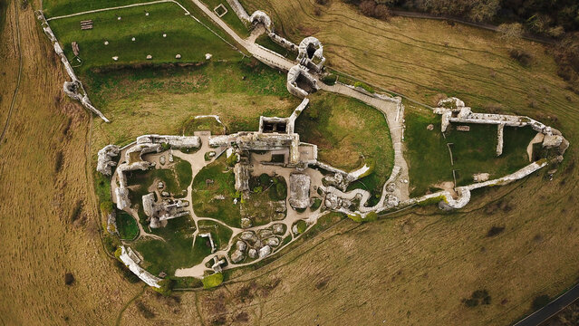 Aerial view of the historic ruins of Corfe Castle, featuring ancient stone walls, grassy courtyards, and winding pathways in Corfe Castle, England, United Kingdom.