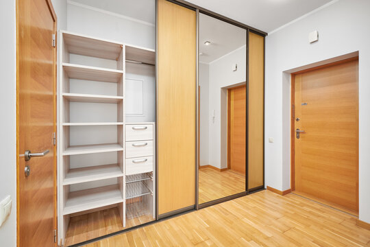 Modern sliding door wardrobe in apartment hallway interior with view to entrance door