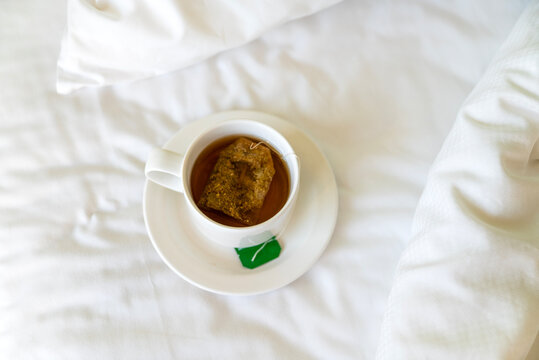 Herbal Tea in a white cup on white sheets in the bed
