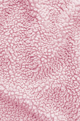 Detailed texture of light pink sherpa fleece fabric. Top view close-up of soft curly textile material for outerwear and interior design softly draped to create an abstract background © DariaR