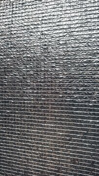 ​A vertical full-frame closeup shot of an embossed metallic thermal insulation foil sheet. Featuring a shiny,