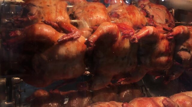 Whole chickens roasting on a rotisserie spit