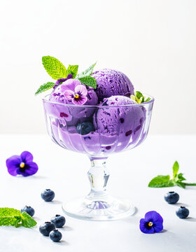 Blueberry ice cream scoops in a fancy glass bowl, fine dining. AI