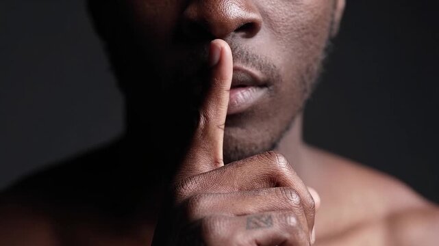 Man holding finger to lips in silence gesture. Quiet, confidentiality and discretion concept. Secret, privacy and communication.
