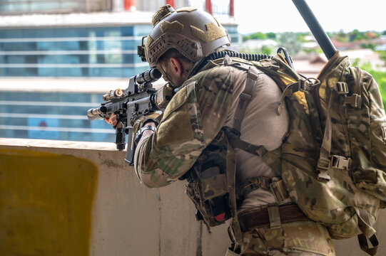 Brave special forces soldier in full tactical protective gear and helmet, holding an assault rifle while courageously patrolling inside  abandoned building