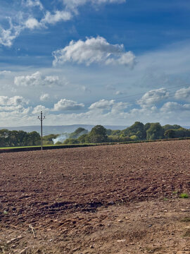 Ploughed Farm Field in Rural Devon Landscape with Telegraphed Pole and Cloud Sky