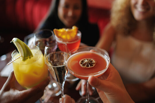 Friends toasting colorful cocktails celebrating at a bar