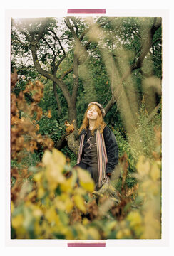 A young woman stands lost in thought among autumn woodland